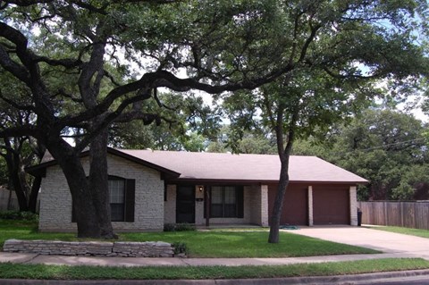 A house with a brown roof and a tree in front of it.