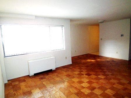an empty living room with a window and a wooden floor
