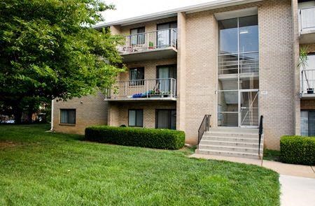 a brick apartment building with green grass and a staircase
