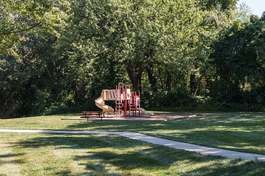 a park with a red swing set in the grass