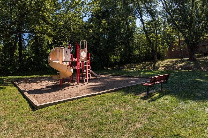 a playground with a slide and a bench in a park