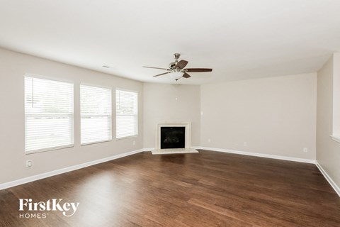 A spacious room with a fireplace and a ceiling fan.