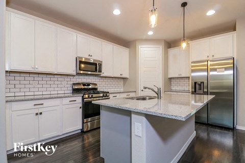 A modern kitchen with white cabinets and stainless steel appliances.