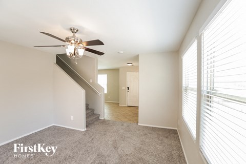 a living room with a ceiling fan and a carpeted staircase