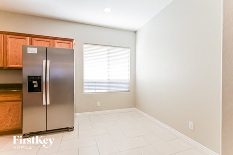 A stainless steel refrigerator in a kitchen with wooden cabinets.