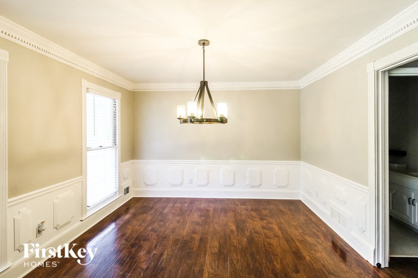 a dining room with wood floors and a chandelier