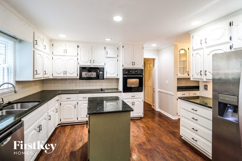 a renovated kitchen with white cabinets and black counter tops and wood floors