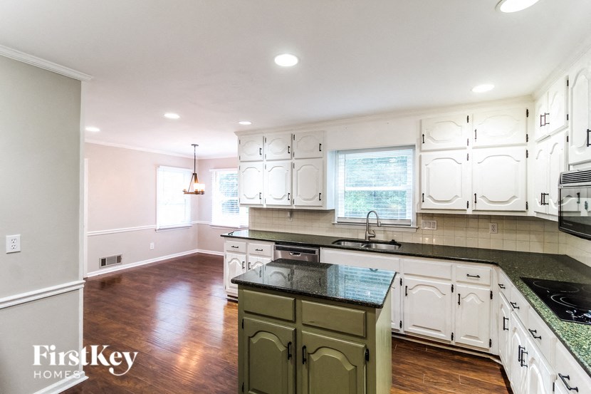 a renovated kitchen with white cabinets and black counter tops and a black counter top island