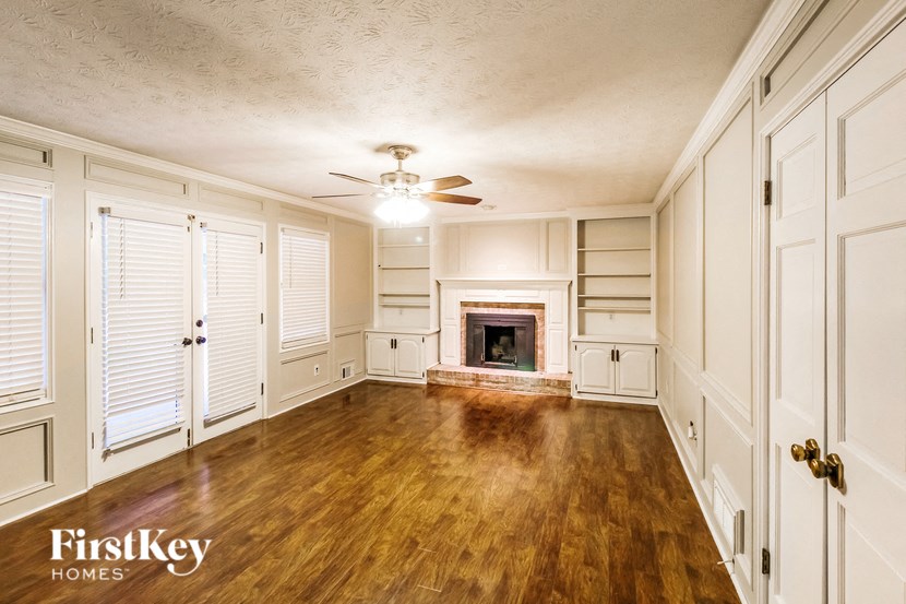 an empty living room with a fireplace and wooden floors