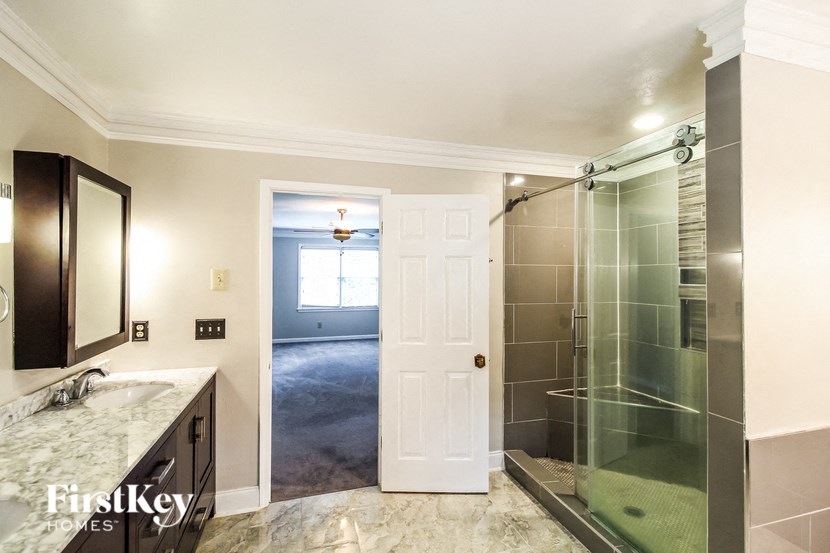a bathroom with a shower and a door to a bedroom