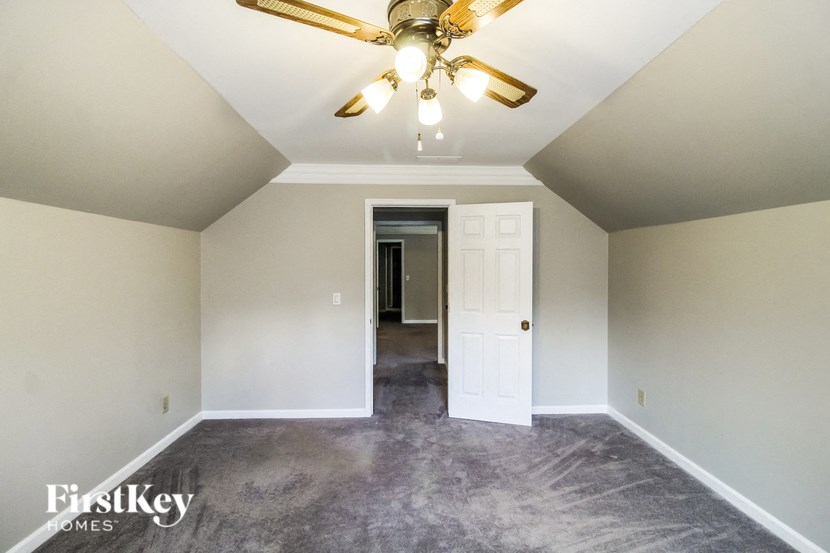 an empty living room with a ceiling fan and a white door