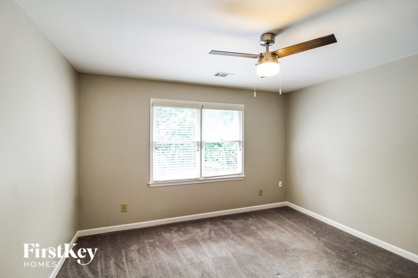 an empty room with a ceiling fan and a window