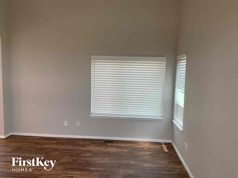 A room with wooden floors and a window with blinds.