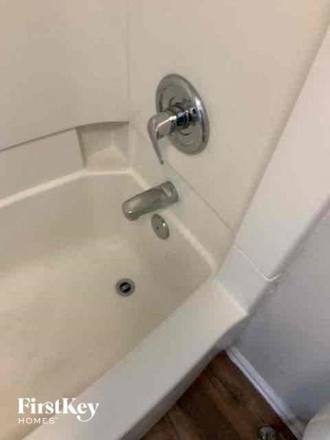 A white bathtub with a silver faucet and a silver handle.