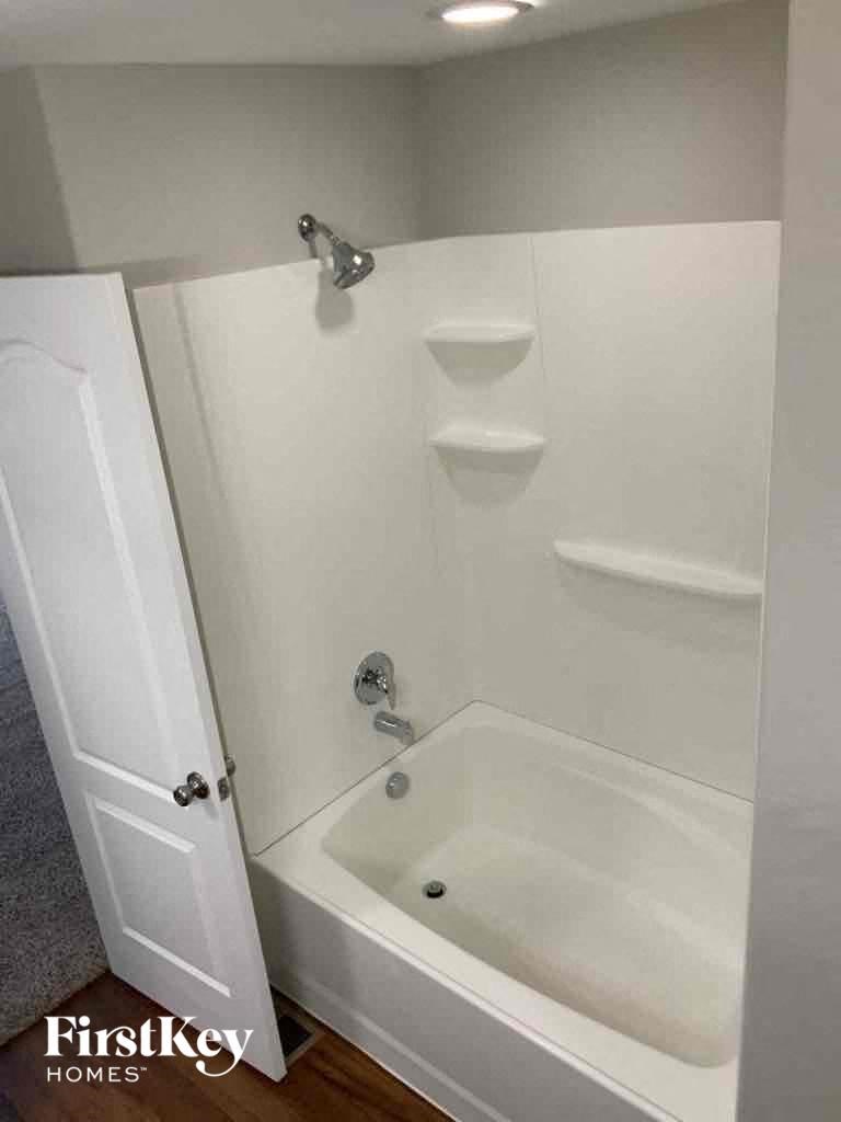 A white bathroom with a bathtub and a door.