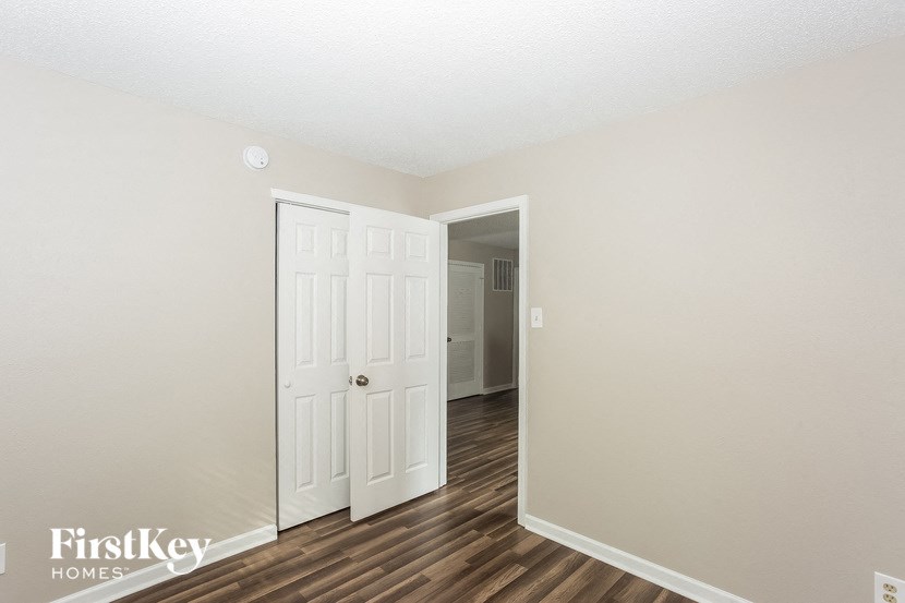 the living room and entrance to a bedroom with wood flooring