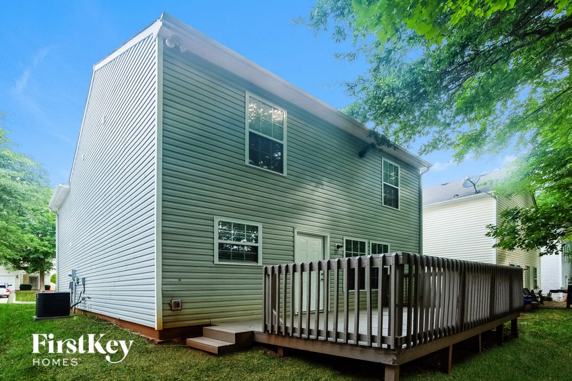 a tiny house with a deck and a fence in a yard