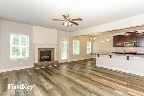 A spacious living room with wood flooring and a fireplace.