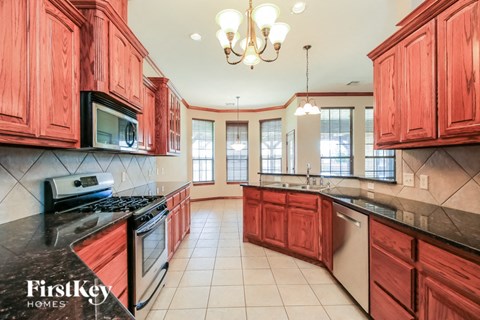A kitchen with red cabinets and a black stove top oven.