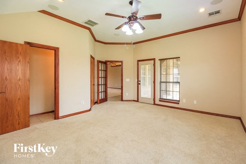 A spacious room with a ceiling fan and wooden doors.