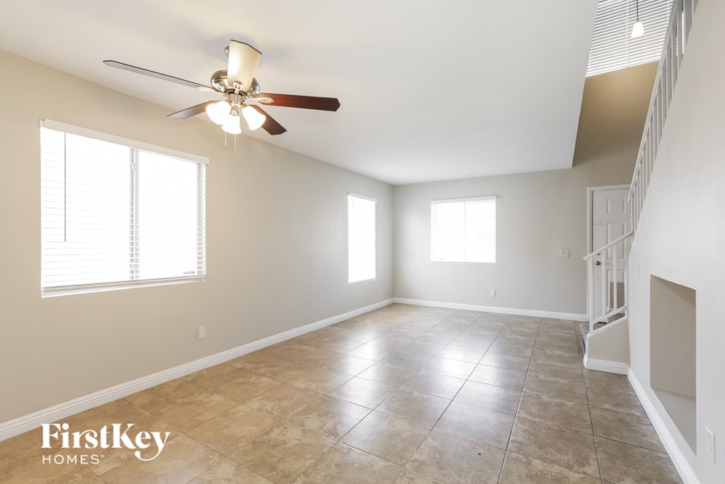 a clean and empty living room with a ceiling fan