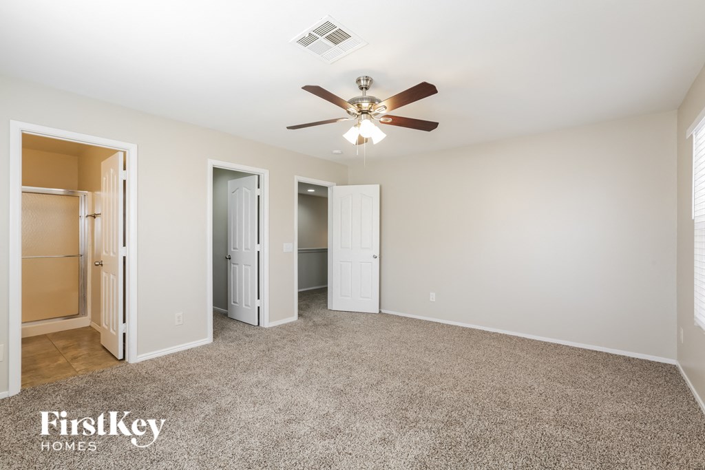 a spacious living room with a ceiling fan and a closet