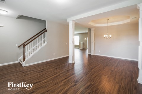 A spacious room with wooden floors and a staircase.