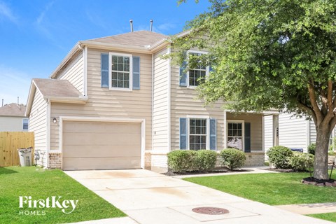 A two-story house with a garage and a tree in front.
