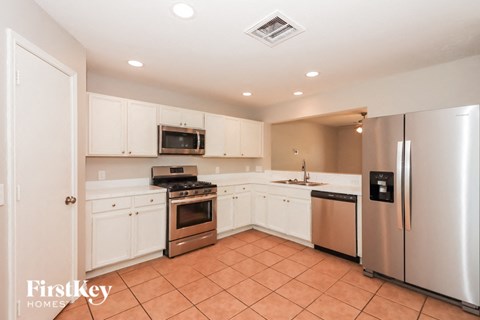 A kitchen with a stove top oven, microwave, refrigerator, and sink.