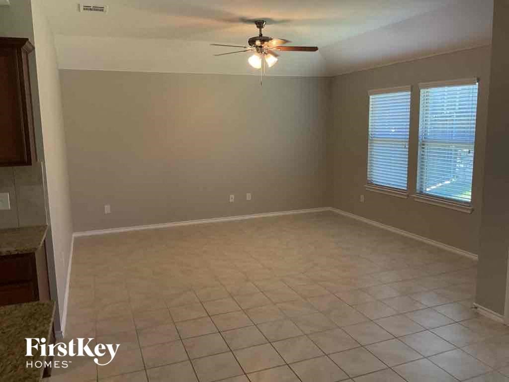 an empty living room with a ceiling fan and a tiled floor