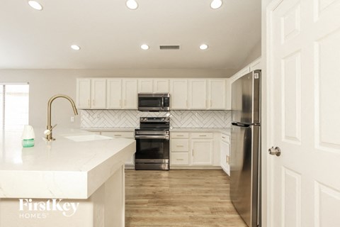a white kitchen with stainless steel appliances and white counter tops