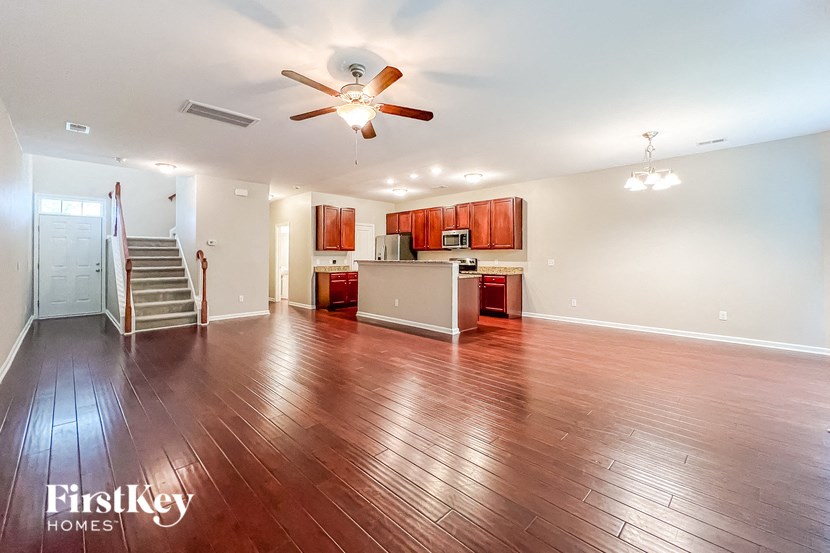 a empty living room with a ceiling fan and a kitchen