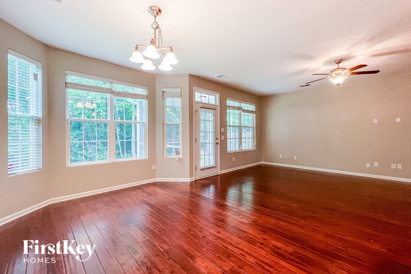 an empty living room with wood floors and a ceiling fan