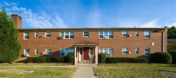 a brick building with a red door and a lawn