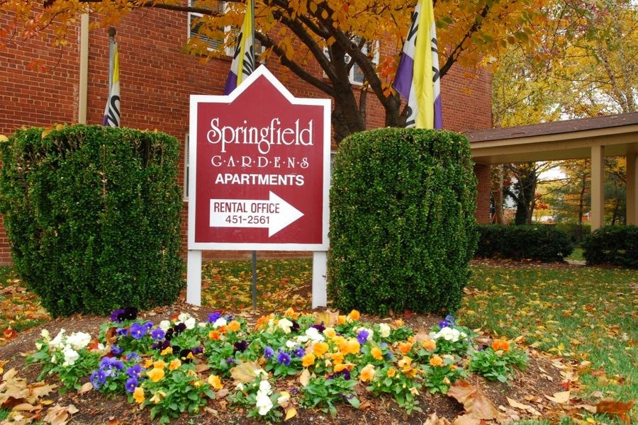 a sign gardens apartments in front of flowers