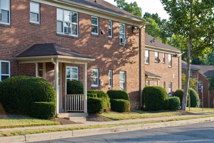 a brick house with a porch in front of a street