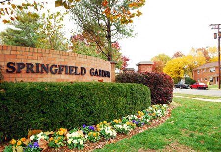 a sign for the garden in front of a garden of flowers