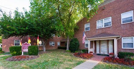 a brick apartment building with a yard and trees
