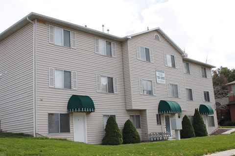 A two-story apartment building with a green awning on the front.