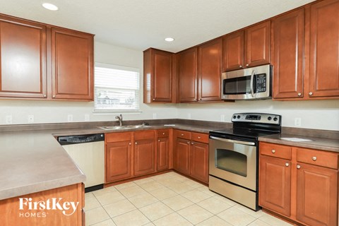 A kitchen with brown cabinets and a stove top oven.
