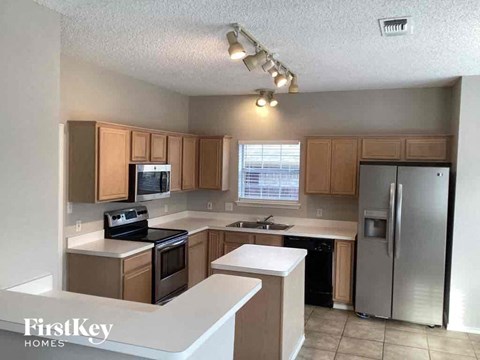 A kitchen with wooden cabinets and a stainless steel refrigerator.