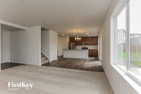 A spacious, empty room with a carpeted floor and a large window.