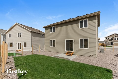 A house with a brown roof and a grey siding is shown with a grassy area in front.