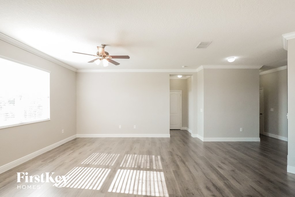 a living room with white walls and a ceiling fan