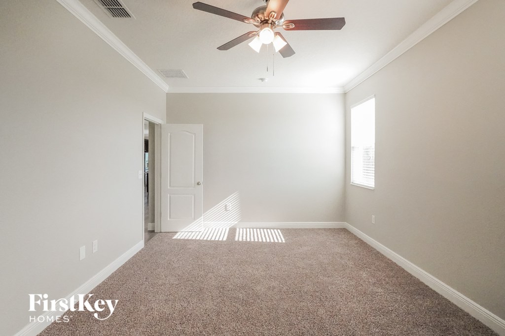 a empty living room with a ceiling fan and a carpet