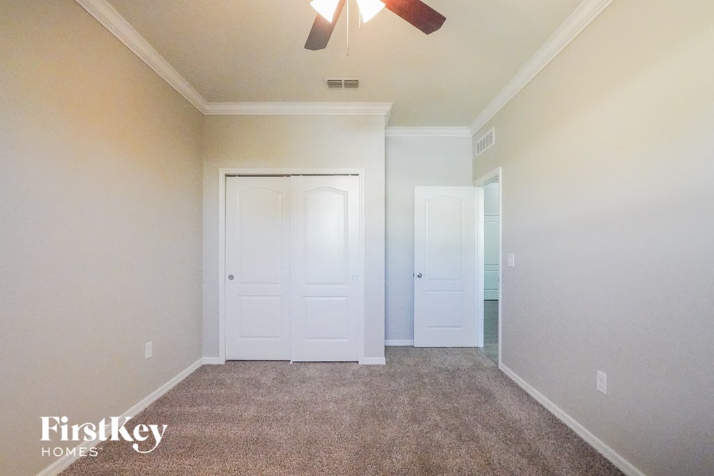 a carpeted room with white doors and a ceiling fan