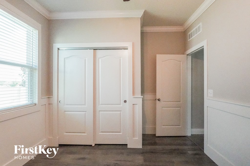 a bedroom with white doors and a closet and a window