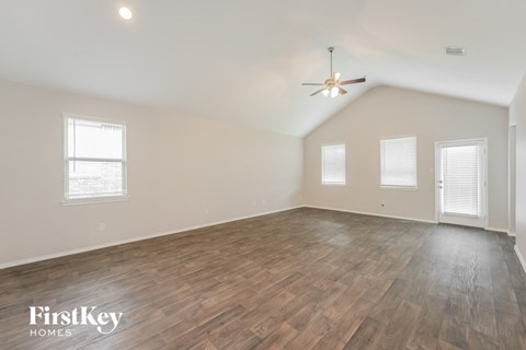 A spacious room with wooden flooring and a ceiling fan.