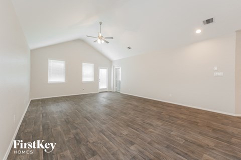 A spacious room with wooden flooring and a ceiling fan.
