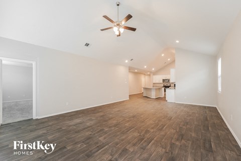 A spacious room with wooden flooring and a ceiling fan.